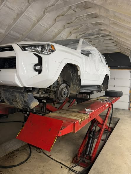 White SUV masked off and raised on the lift before treatment