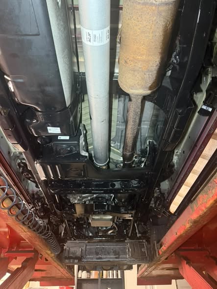 Undercarriage after coating, with an even dark protective film over the frame and floor pan