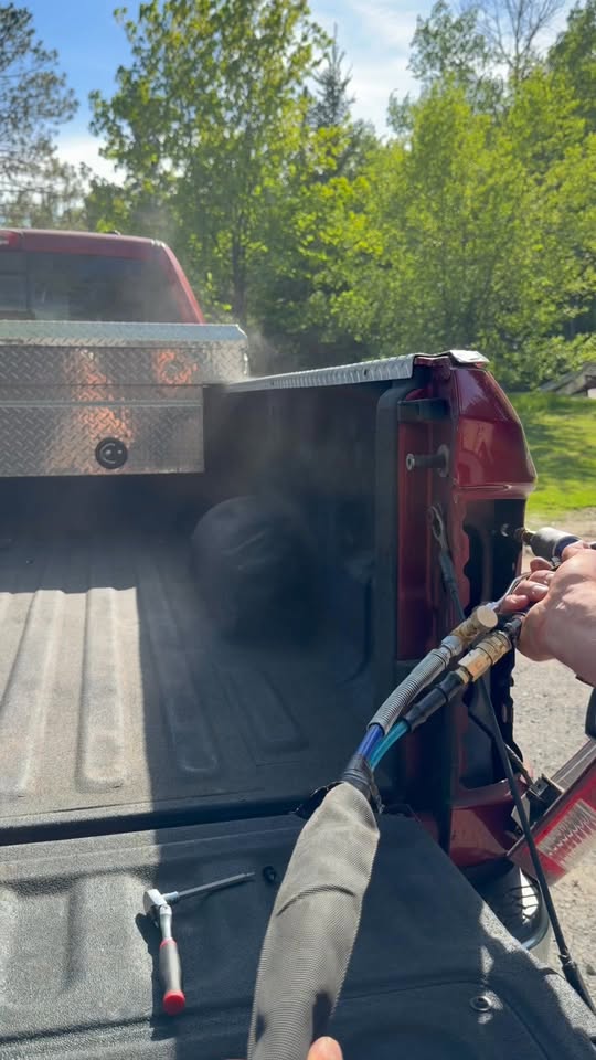 Coating being applied to a pickup truck bed outdoors